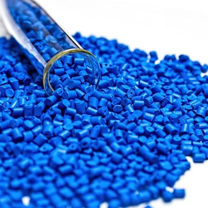 Blue granulated material is spread out on a white surface. A glass tube lies on it's side, partially filled with granules.
