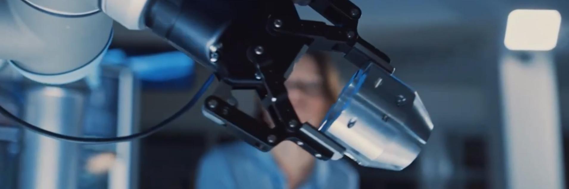 A robotic arm in focus before a woman