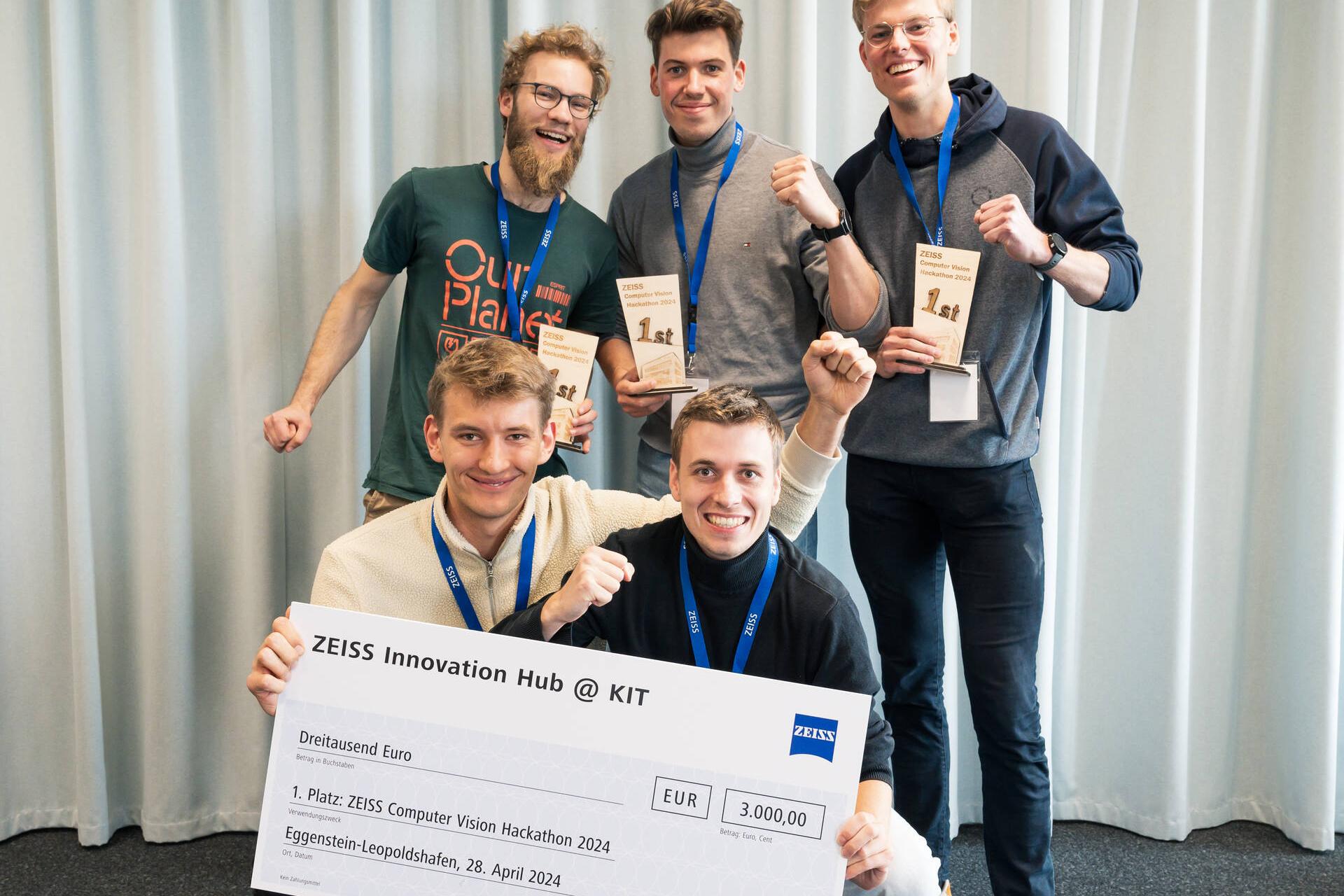 A group photo of the winner team of the ZEISS Computer Vision Hackathon 2024. Two of the five participants are holding a giant cheque