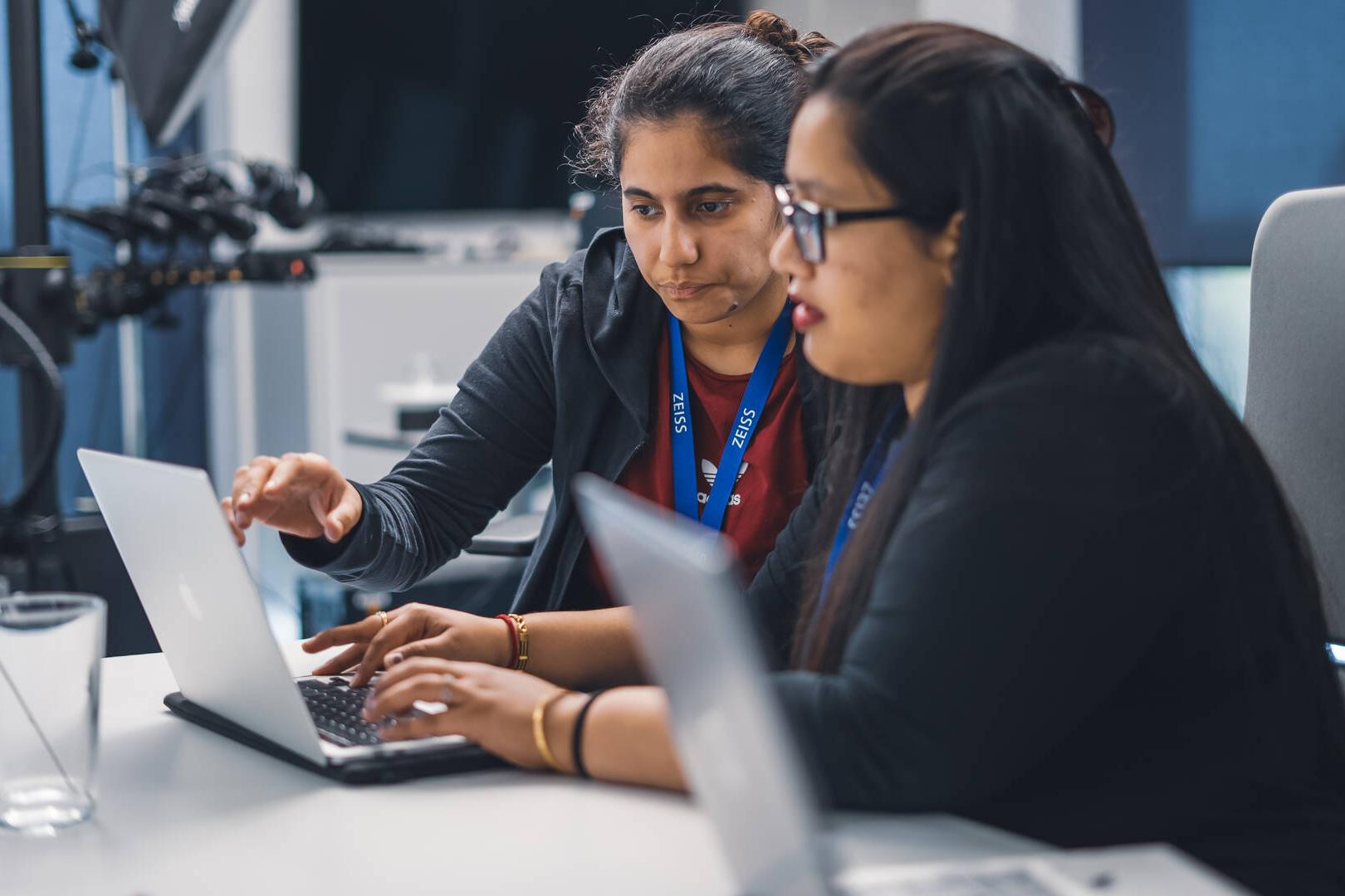 Two hackathon participants sitting at a desk working together on their project.