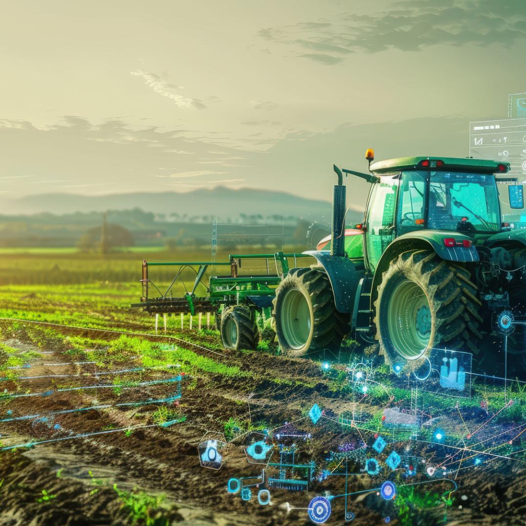 A tractor drives across a field toward the sunset.