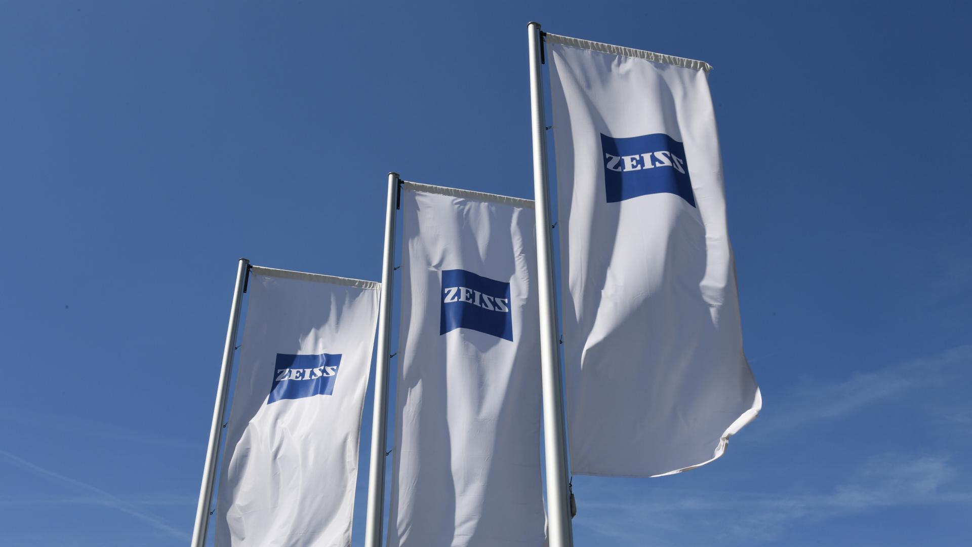 White flags with ZEISS logo in front of a blue sky