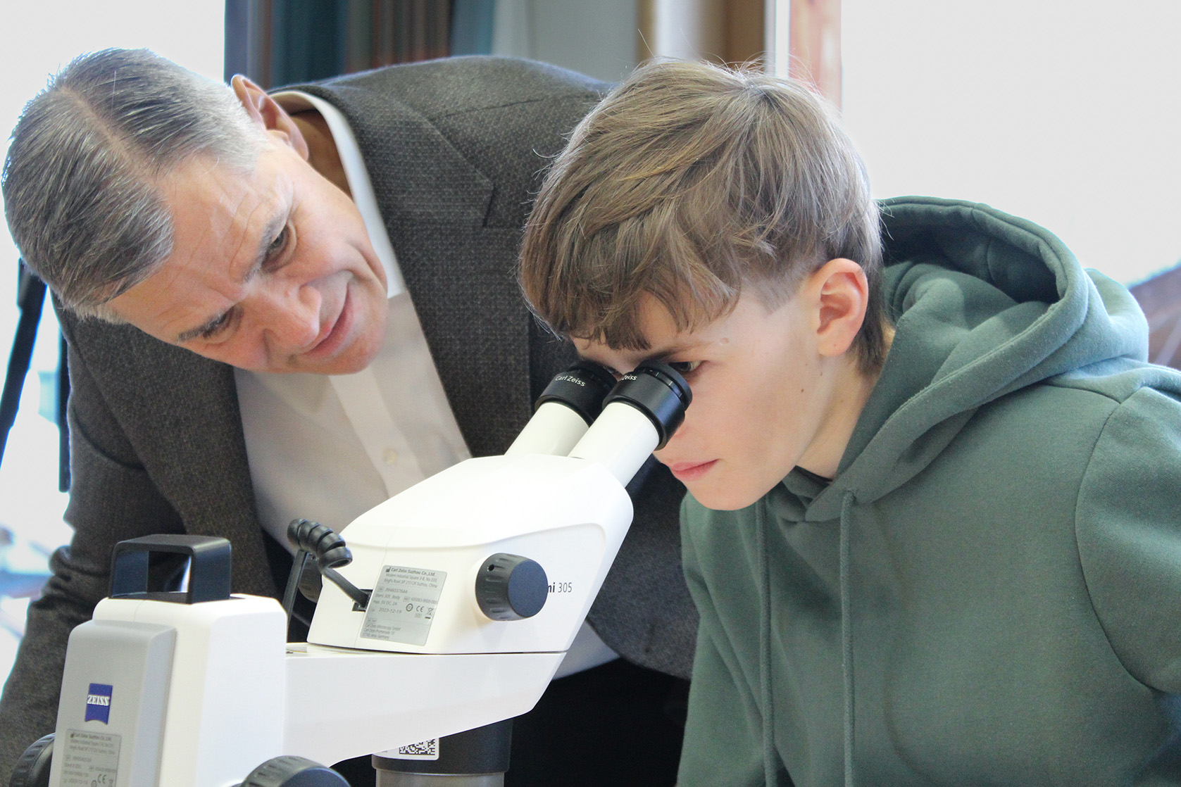 Karl Lamprecht watching trough a microscope with a kid
