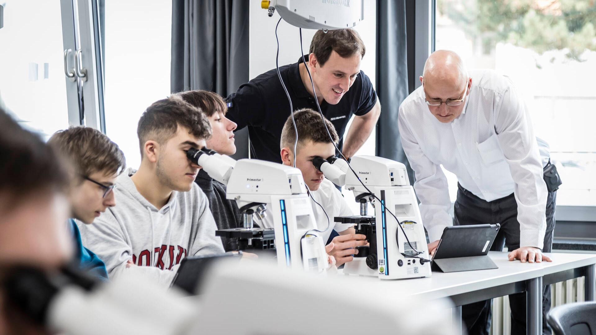 School children in a classroom use microscopes to do their work