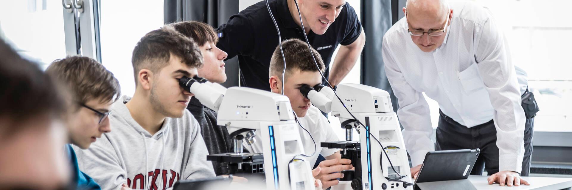 School children in a classroom use microscopes to do their work