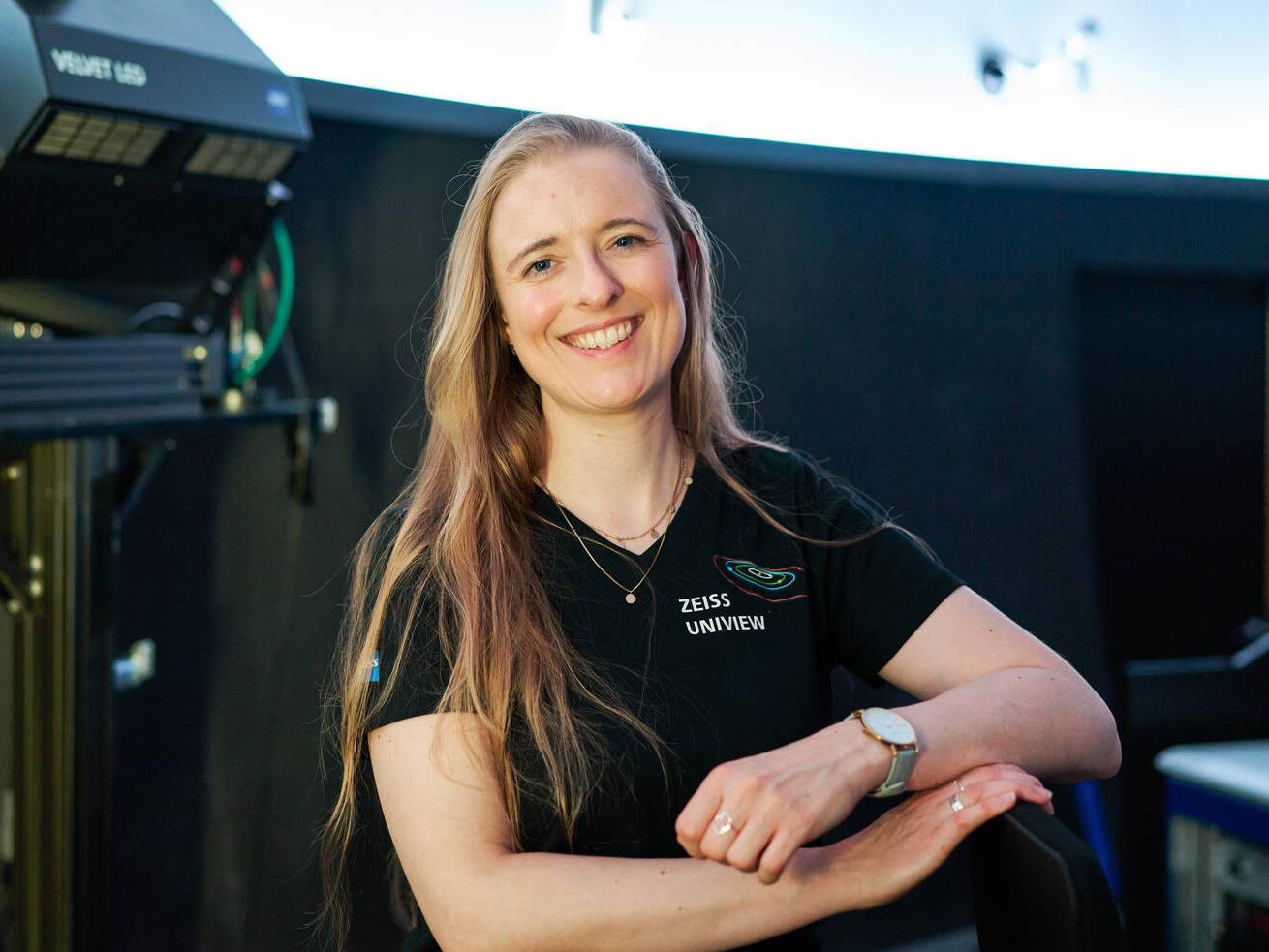 Sophia Dannberg standing in front of a projector in the planetarium.