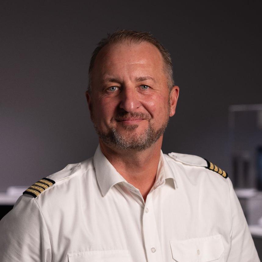 Commercial pilot Tino Janke stands in a showroom and looks into the camera.