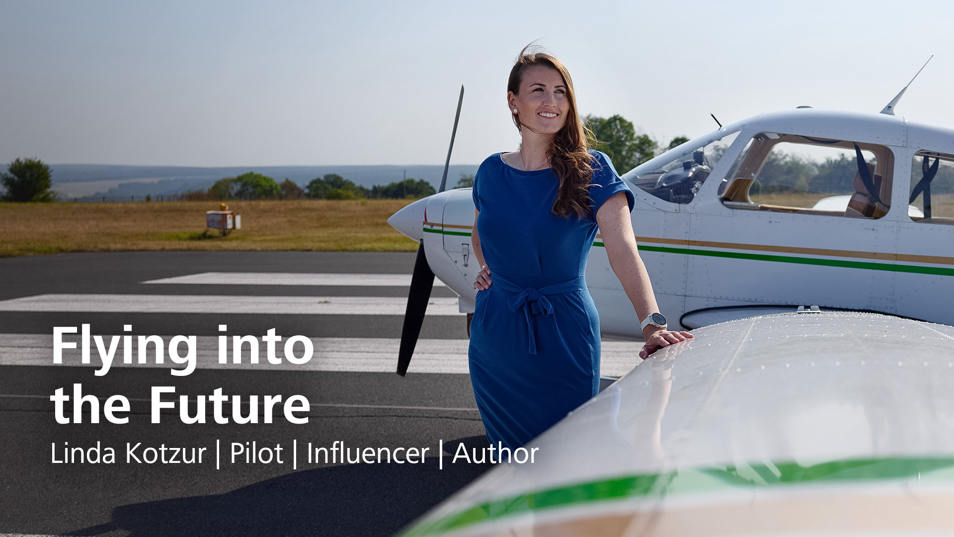 Pilot Linda Kotzur stands leaning against the port wing of her plane on the tarmac, looking past the camera into the distance.