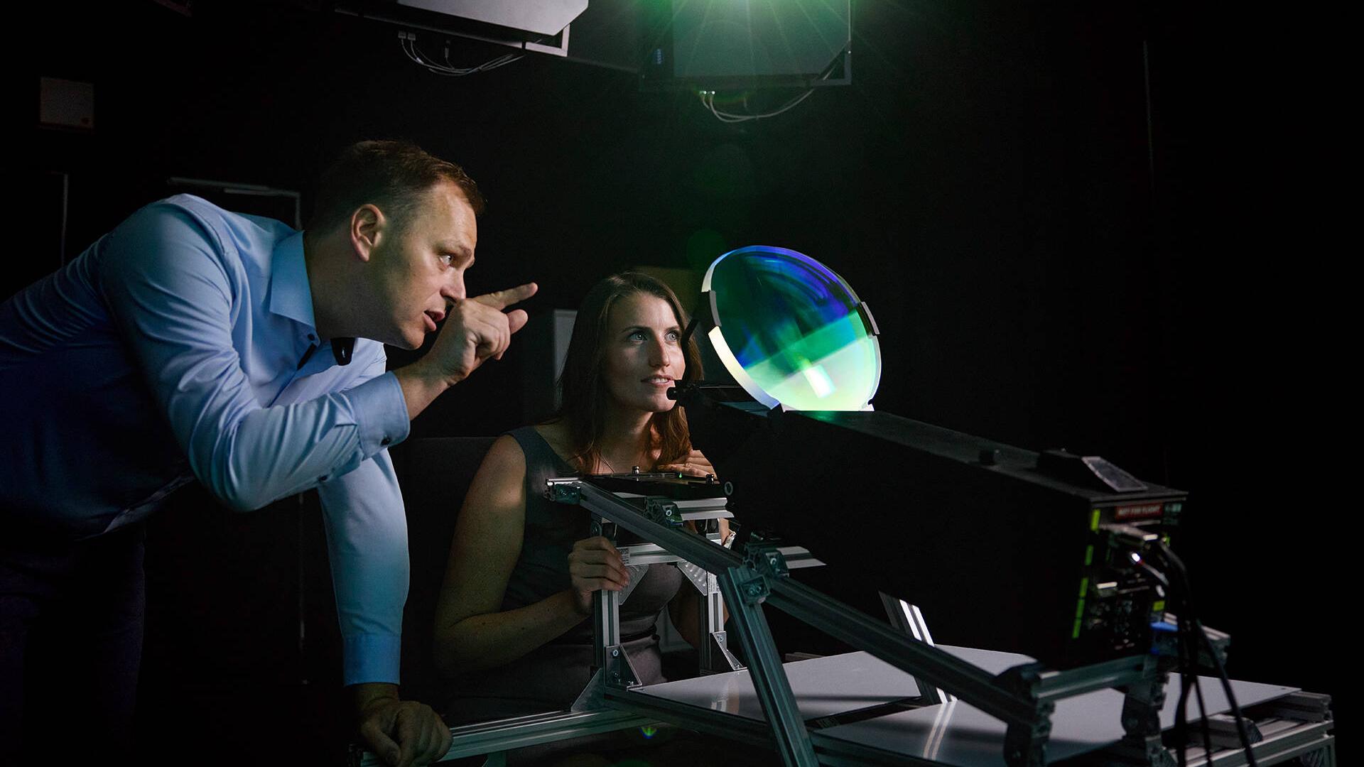 A man and a woman look through a shimmering green window – a head-up display.