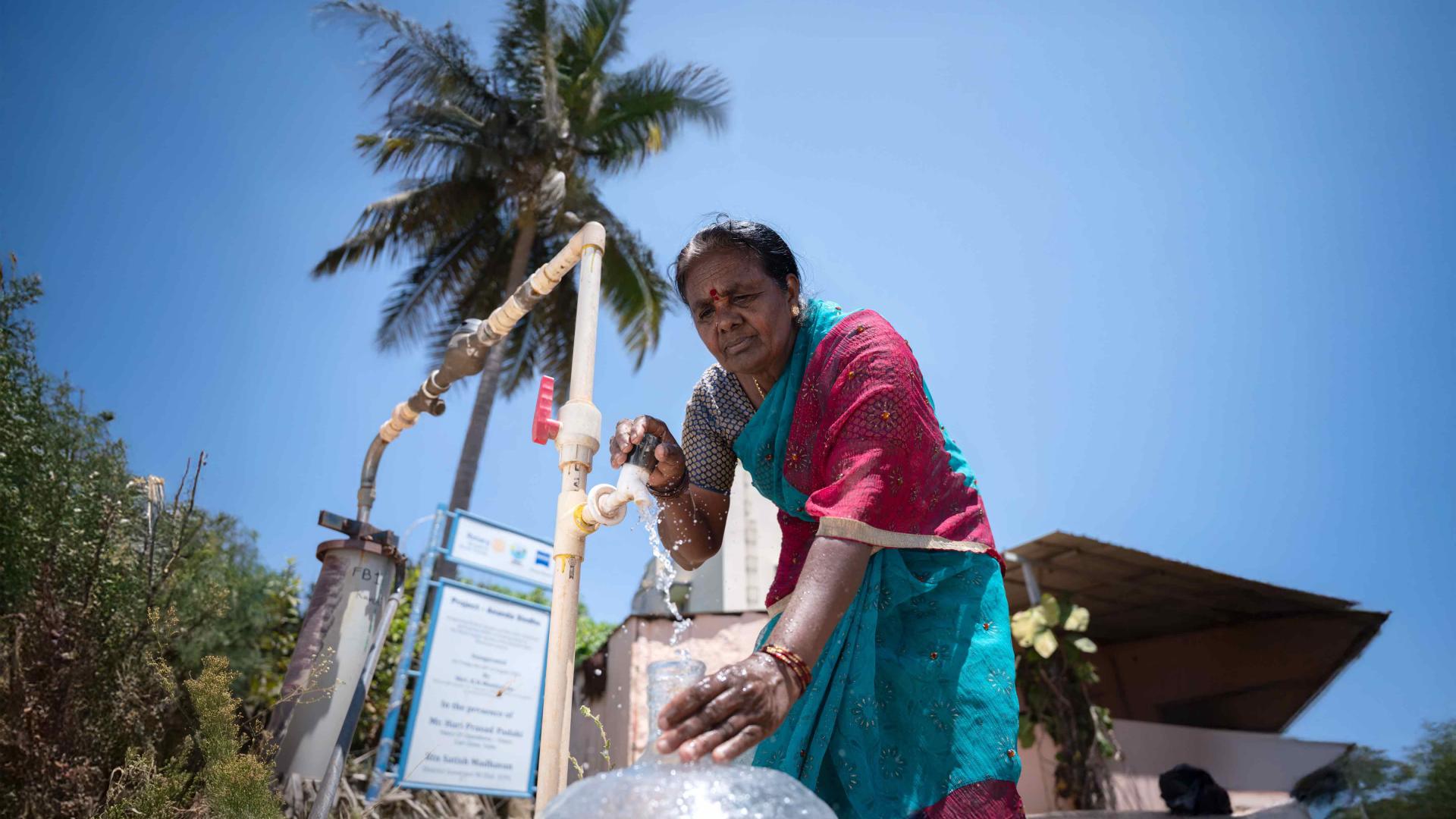 A woman filling a container with water from a faucet