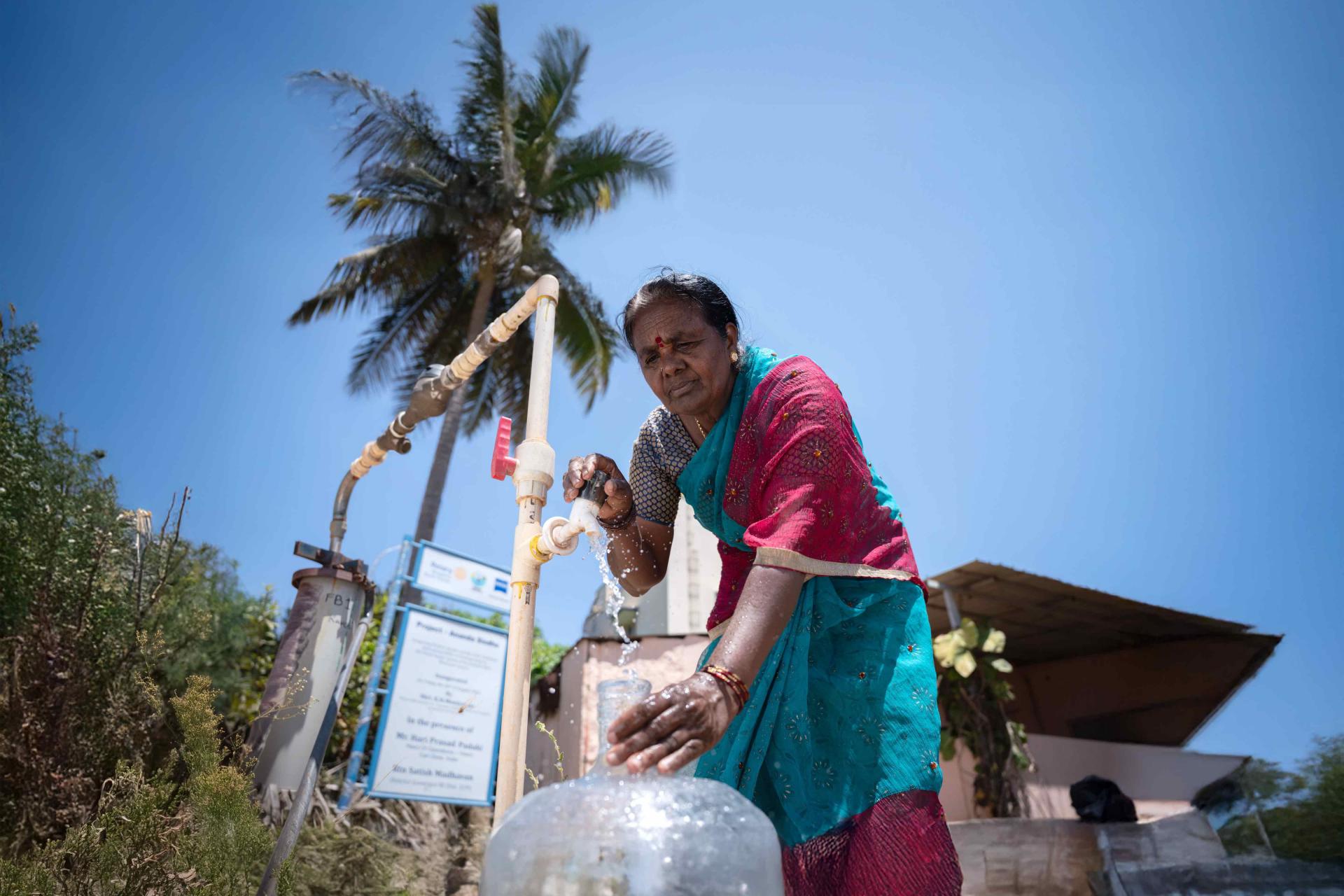 A woman filling a container with water from a faucet