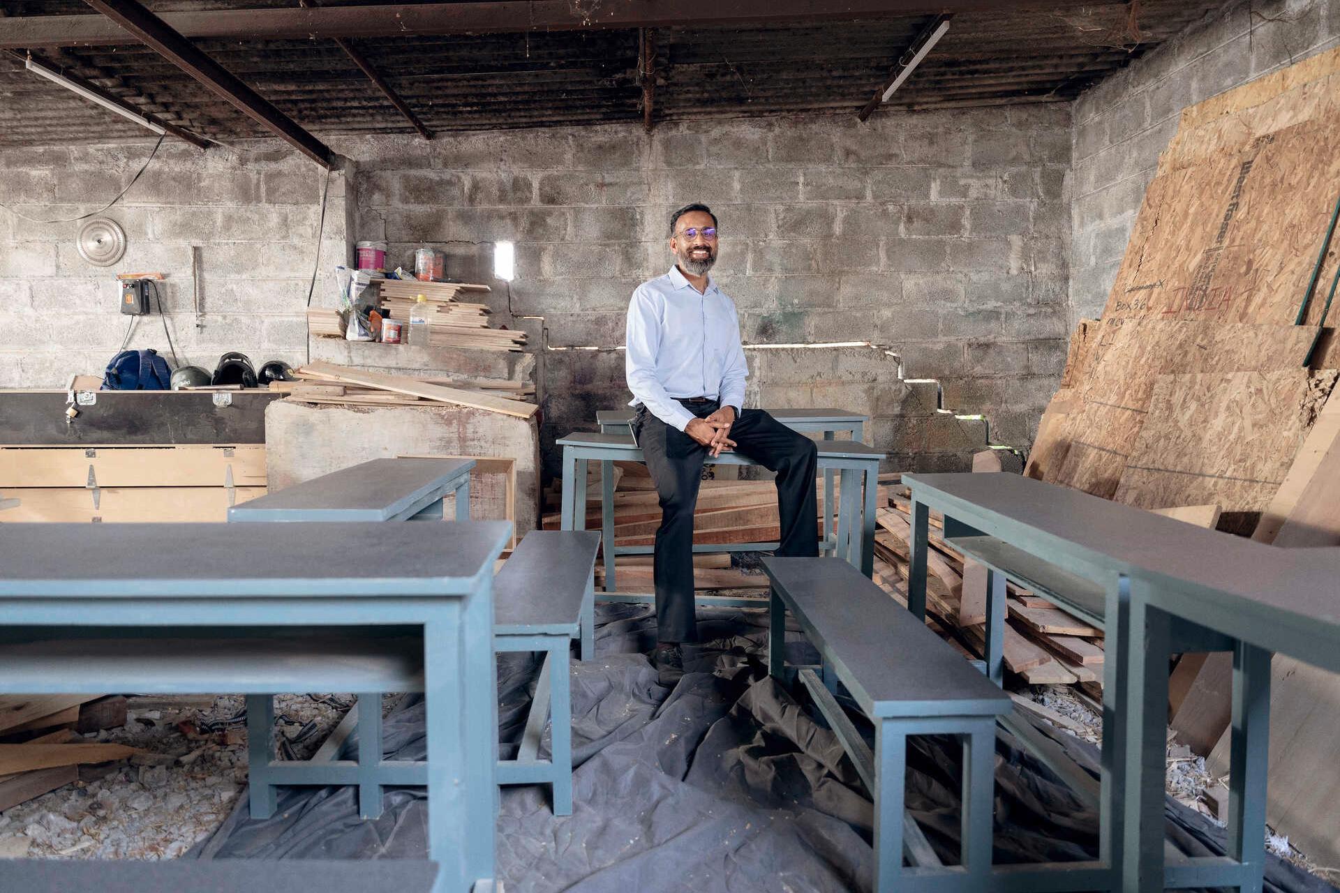 Manoj Sharma sits on a bench in the wood workshop