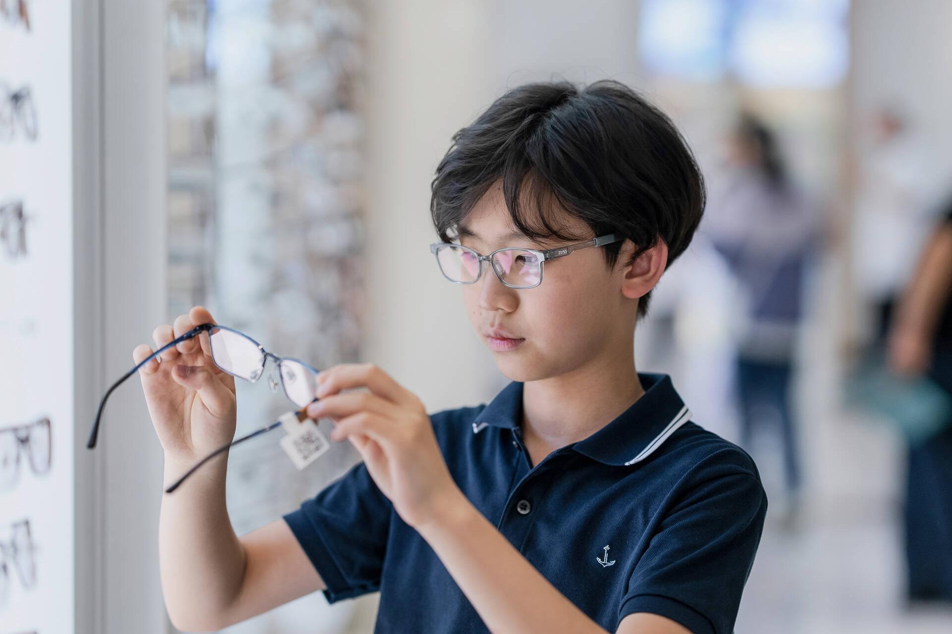 Aidan Zhong looking at a pair of new glasses
