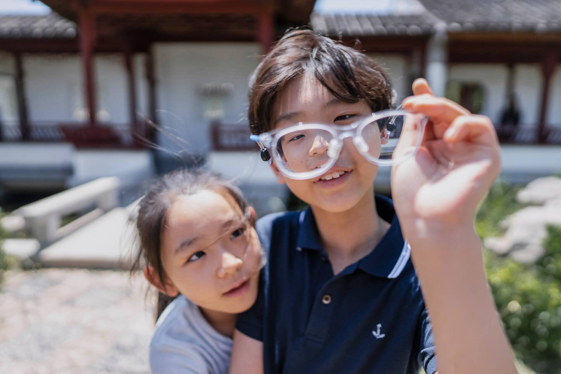 Aidan and Reese Zhong looking at a pair of glasses