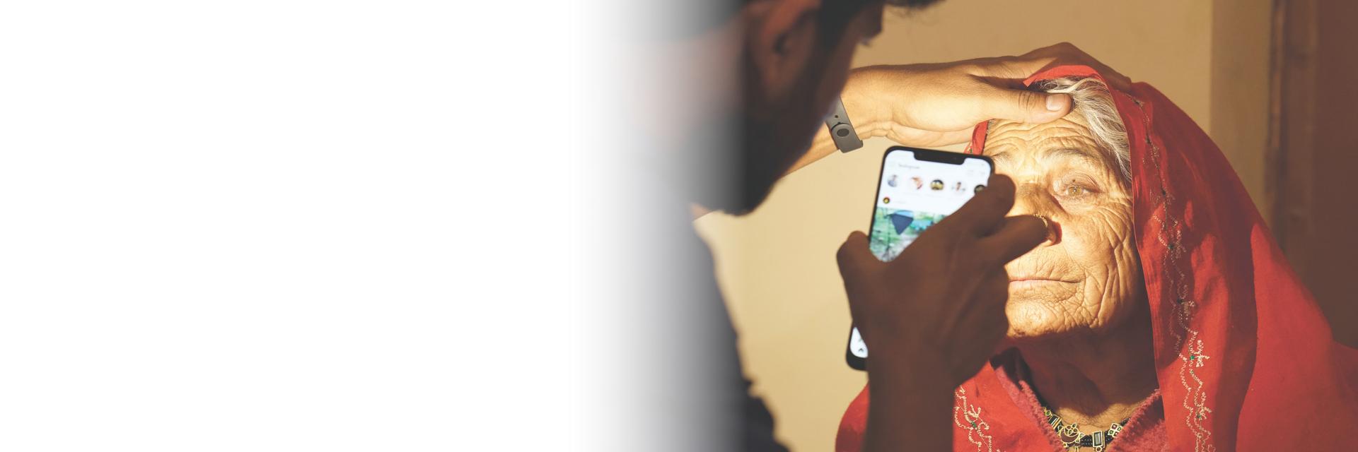 Someone shines a cell phone in an elderly woman's eyes.