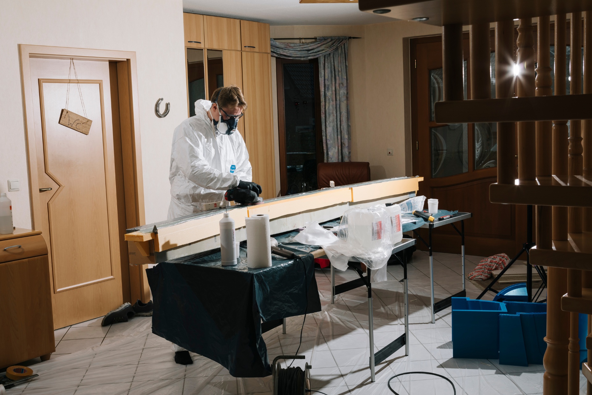 Eine Person in Schutzkleidung arbeitet in einer Werkstatt an Laminier- und Schleifarbeiten für Flugzeugteile.