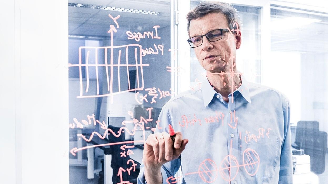 Dr. Michael Totzeck beim Schreiben von wissenschaftlichen Diagrammen und Notizen auf einer Glastafel in einem ZEISS Büro