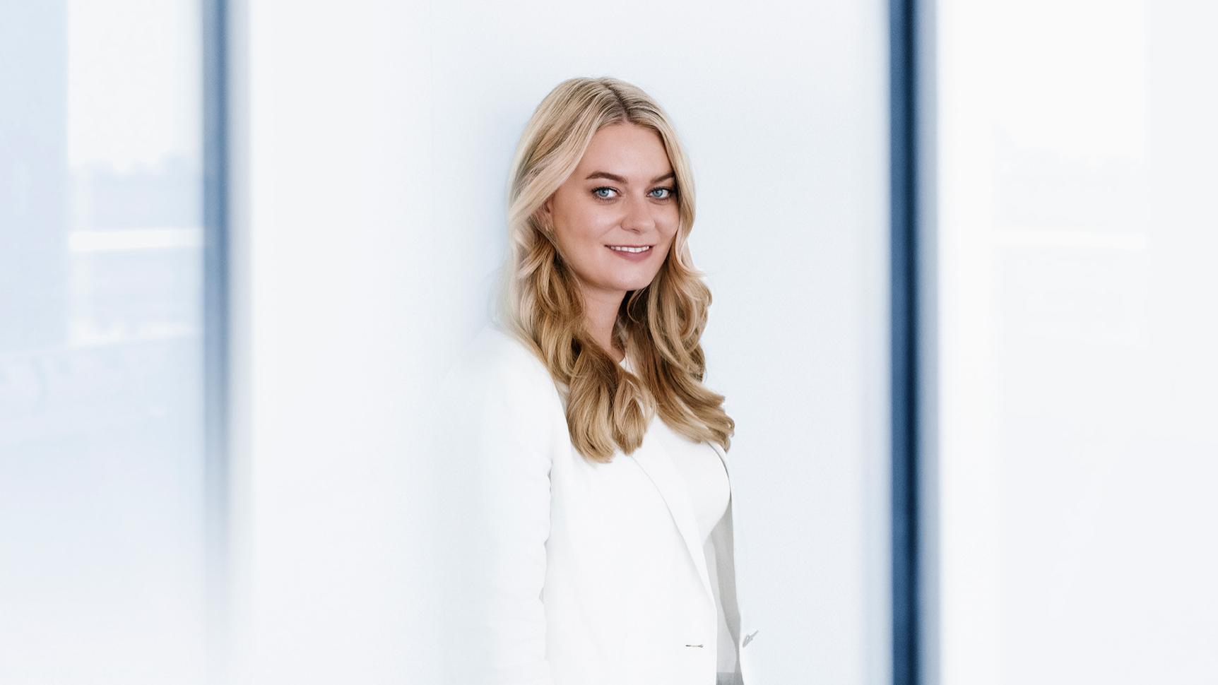 Liesa steht in einem modernen Büro und blickt selbstbewusst in die Kamera