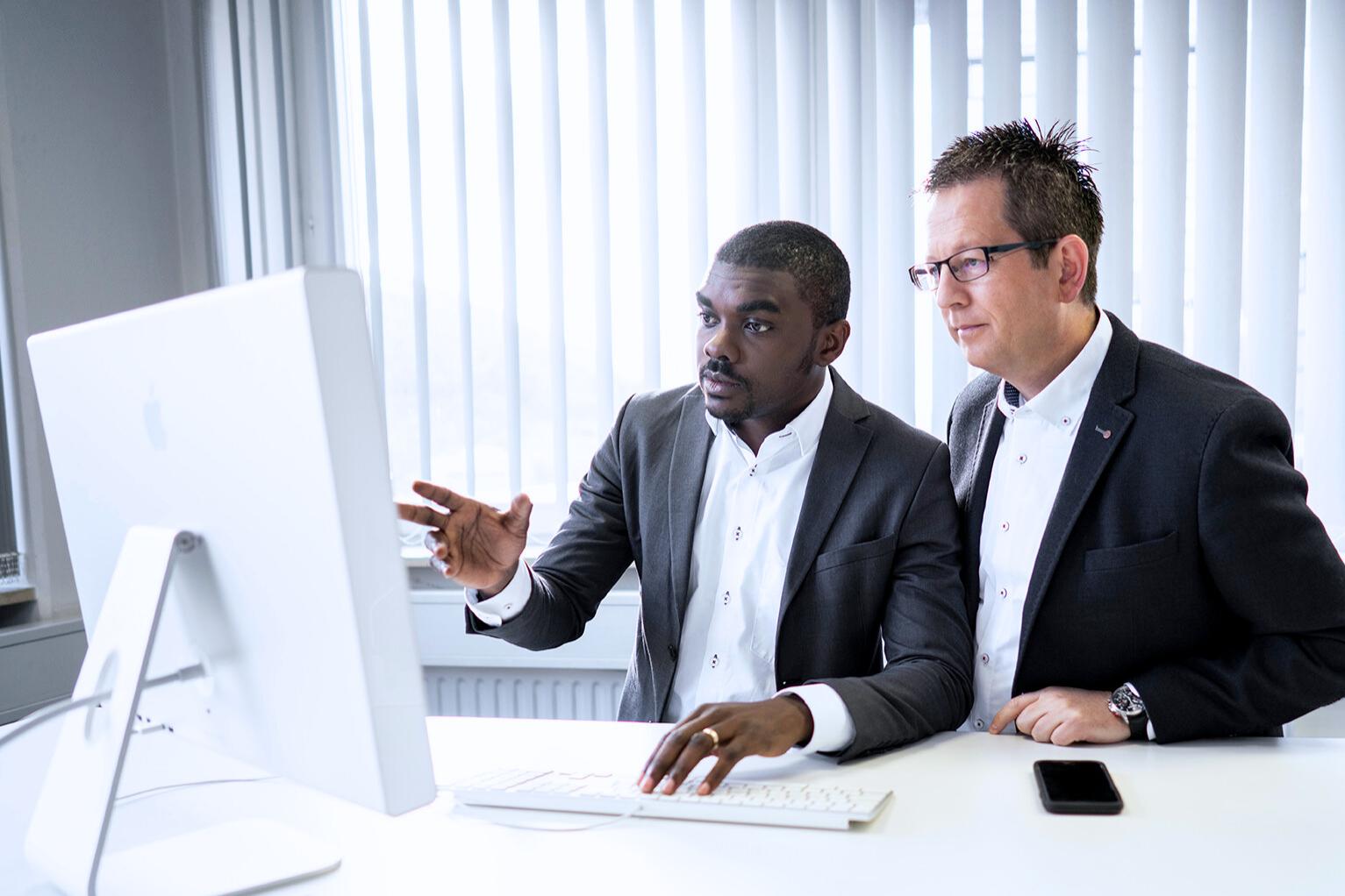 Romeo in discussion with a colleague from his team. Both stand in front of a screen and look at it