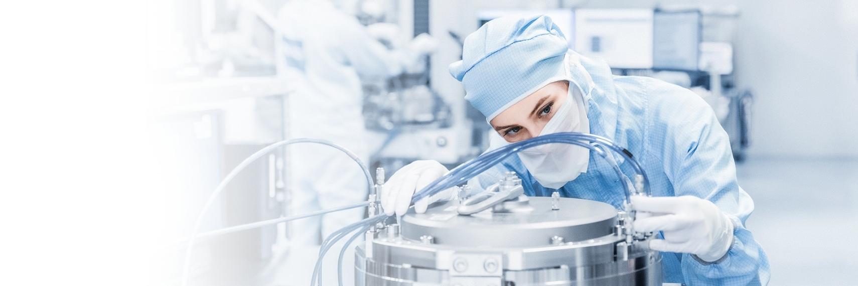 A female employee in a cleanroom suit works in a modern production hall