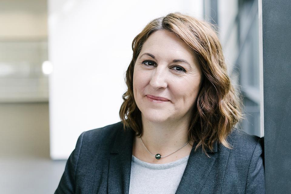 Alexandra befindet sich in einem ZEISS Gebäude und lächelt in die Kamera