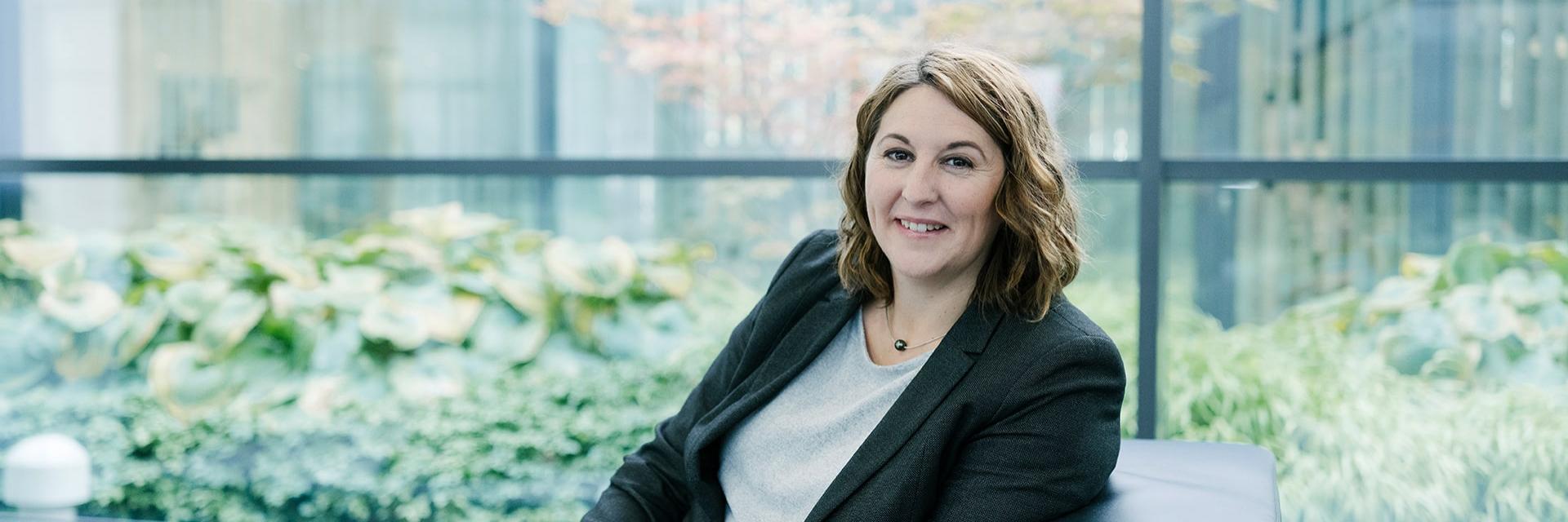 Alexandra befindet sich in der Lounge eines ZEISS Gebäudes und schaut in die Kamera