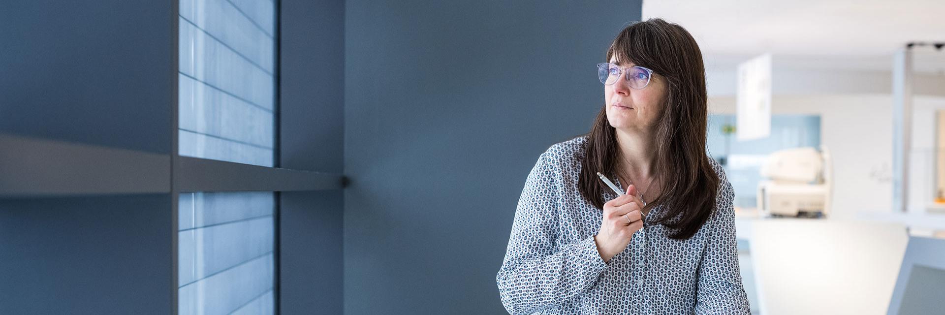 Anna is in a ZEISS building, taking notes and looking thoughtfully into the distance