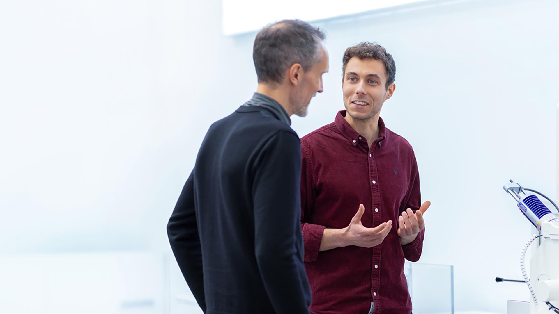 Sébastien working on a device, discussing with a ZEISS colleague with a smile.