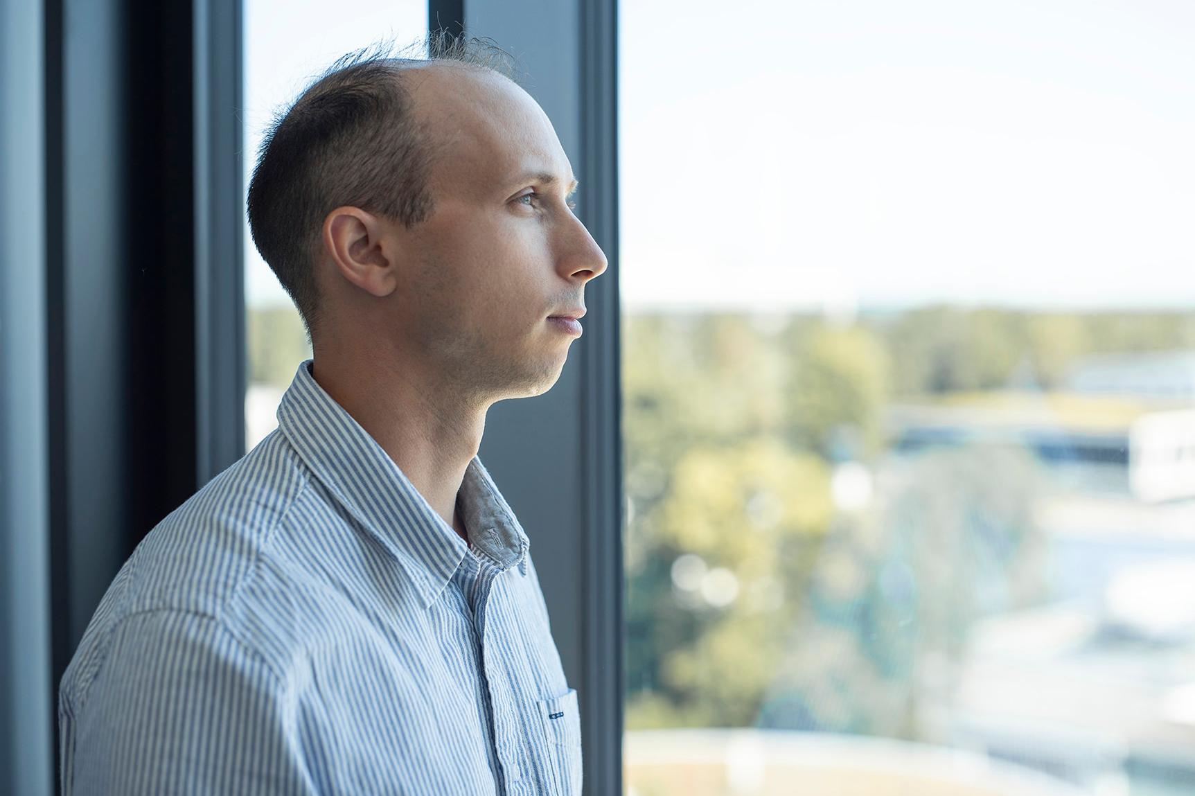 Guillaume blickt nachdenklich aus einem Fenster im ZEISS Büro