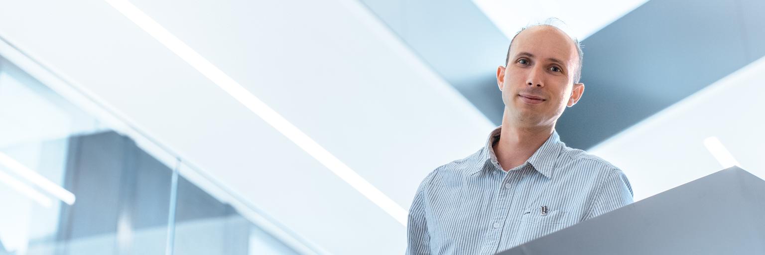 Guillaume steigt die Treppe im ZEISS Bürogebäude hinunter, schaut dabei in die Kamera und grinst freundlich