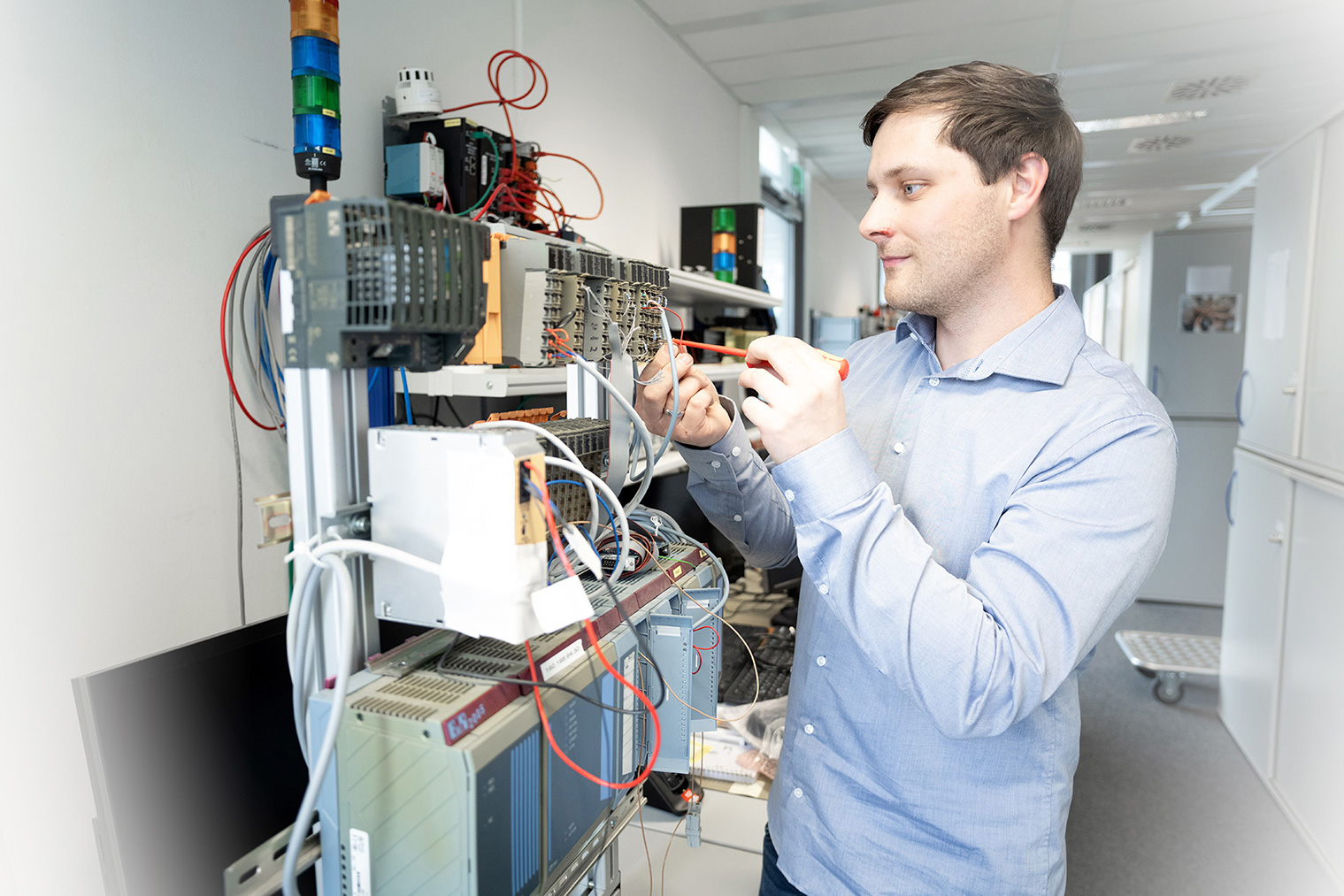 Steffen works on an electrotechnical laboratory setup with various devices and cables.