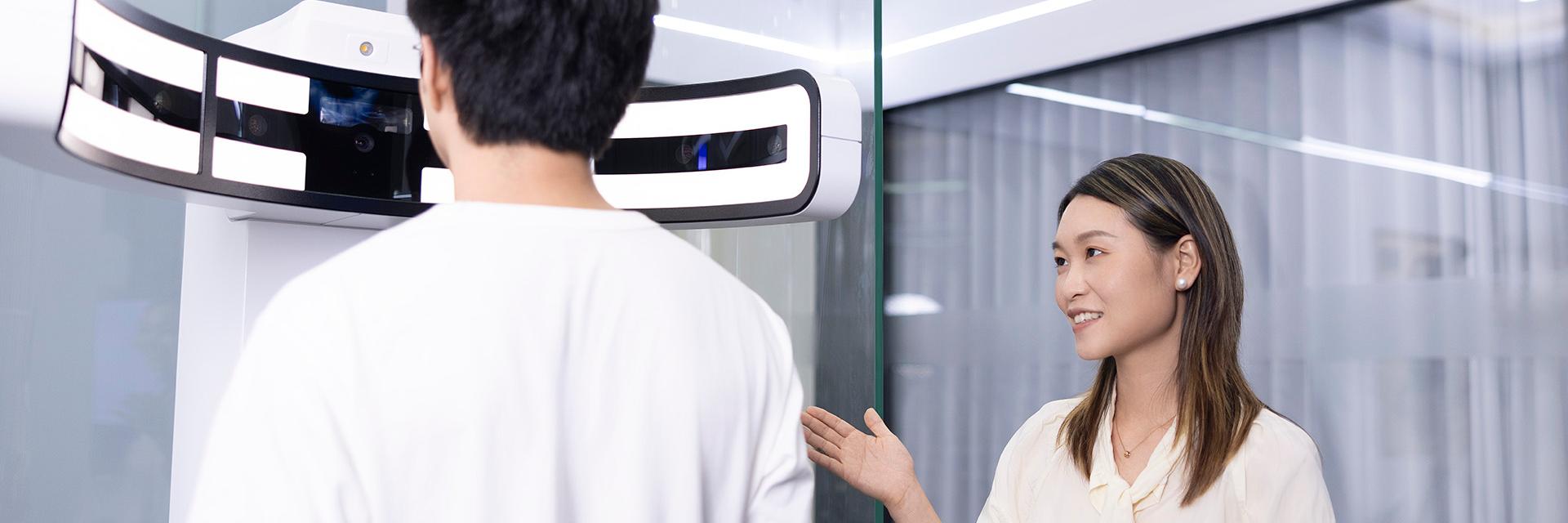 Lizzy explaining the functions of a ZEISS Visufit 1000 Platform to a male customer.