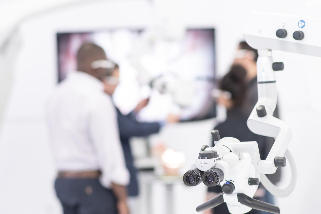 Nahaufnahme eines ZEISS Medizinprodukts. Im Hintergrund betrachtet Michael die Ergebnisse des Medizinprodukts zusammen mit einer Gruppe von Kollegen, die weiße Brillen tragen.