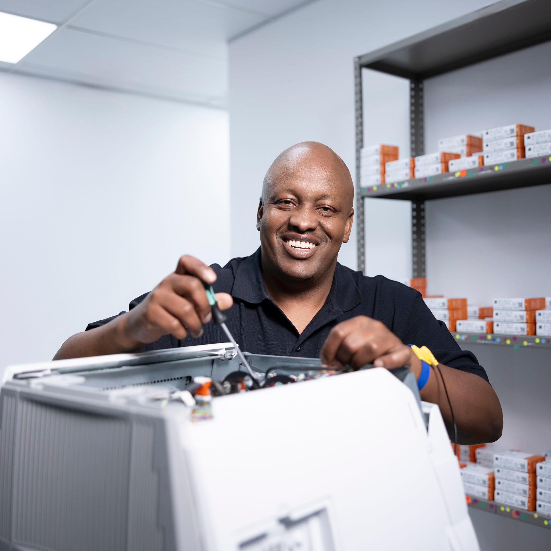 ZEISS senior field service technician Buyani is satisfied and smiles, next to a diagnostic device.