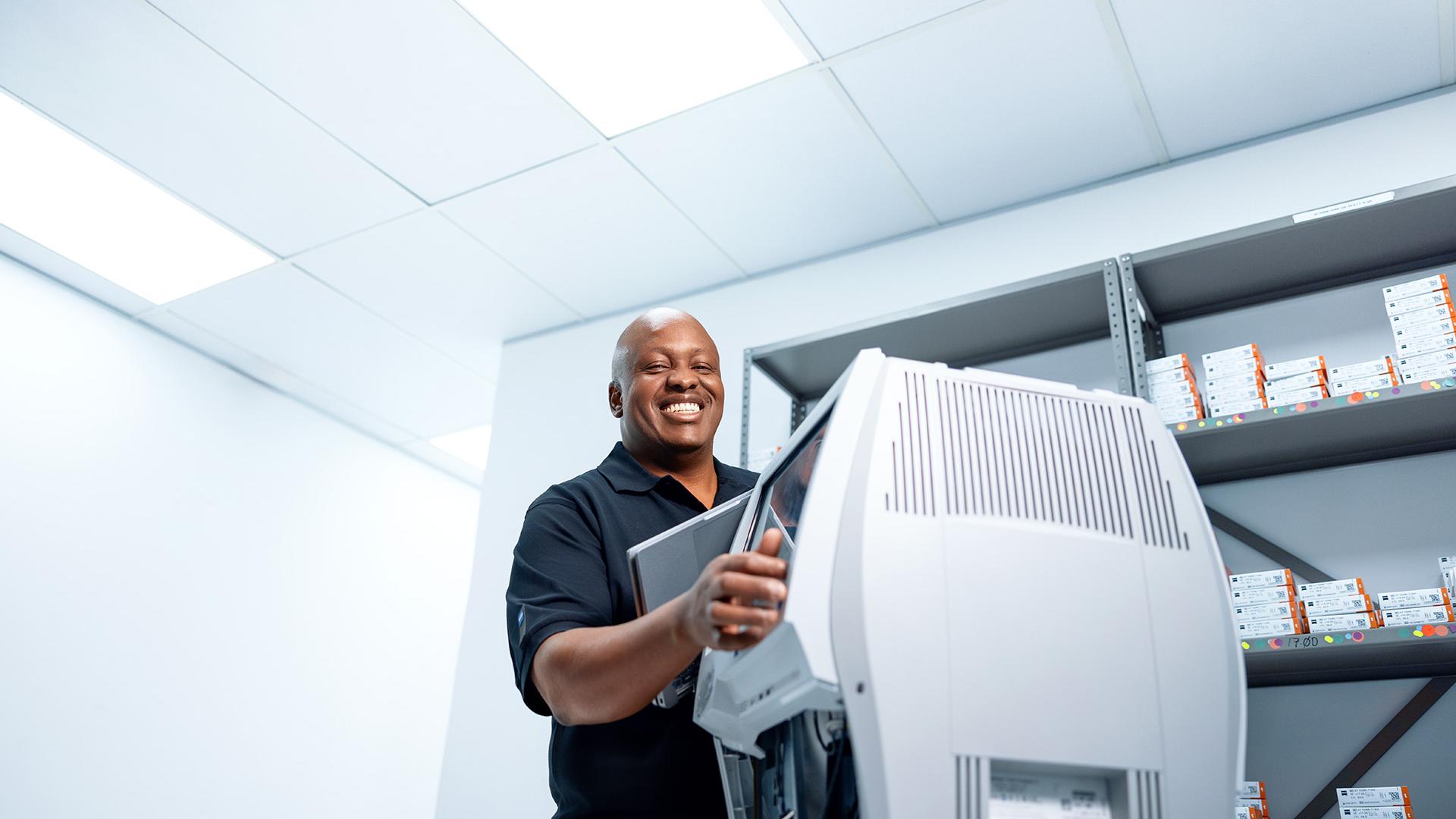 ZEISS field service Engineer Buyani grins broadly while repairing a ZEISS diagnostic device.