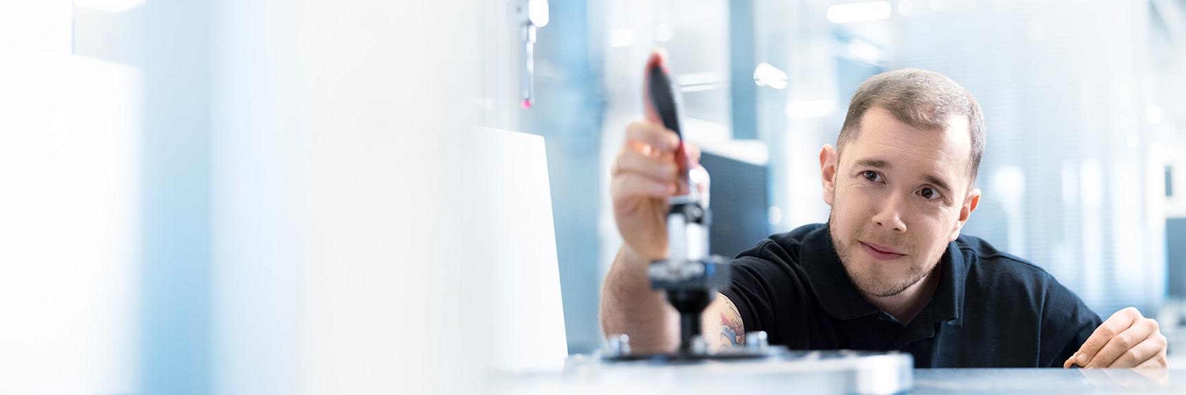 Marwin holds a screwdriver in his hand as he focuses on his work