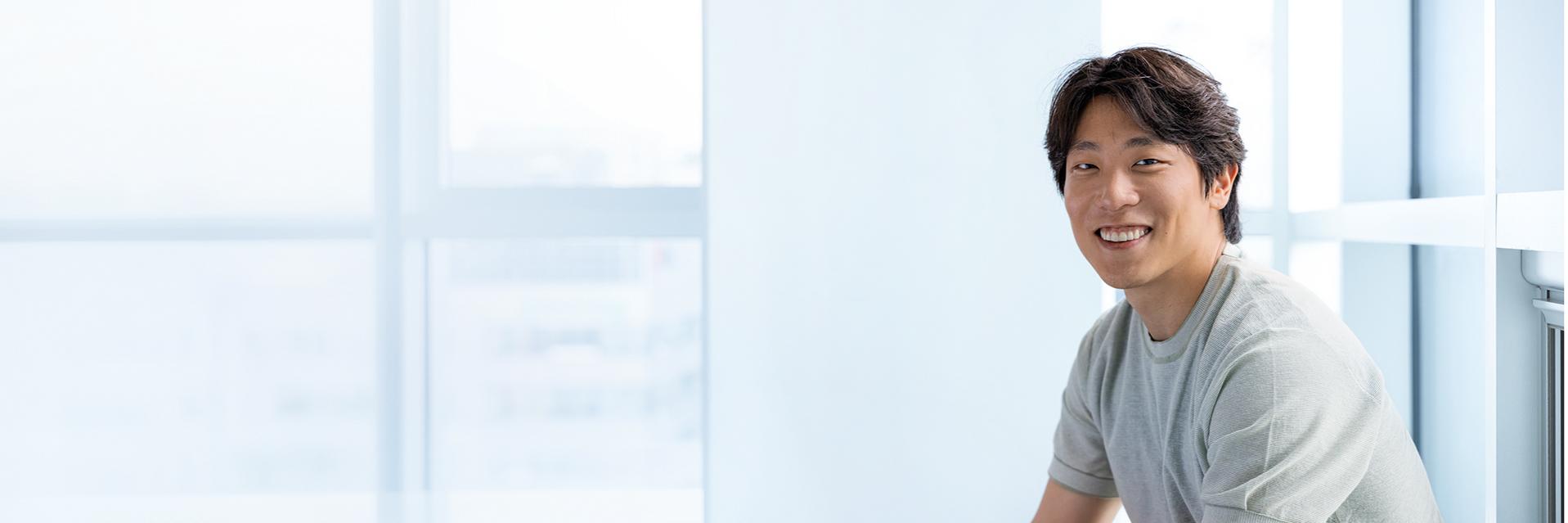 ZEISS employee MinKyue sitting in his office, laughing.