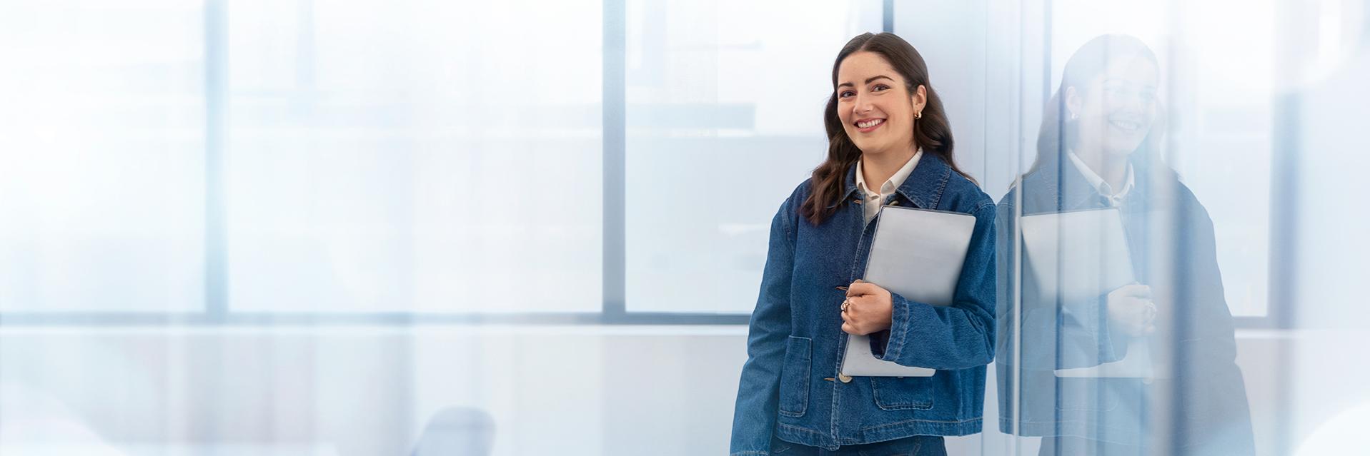 ZEISS Employee, laughing and holding a laptop computer in her hands.