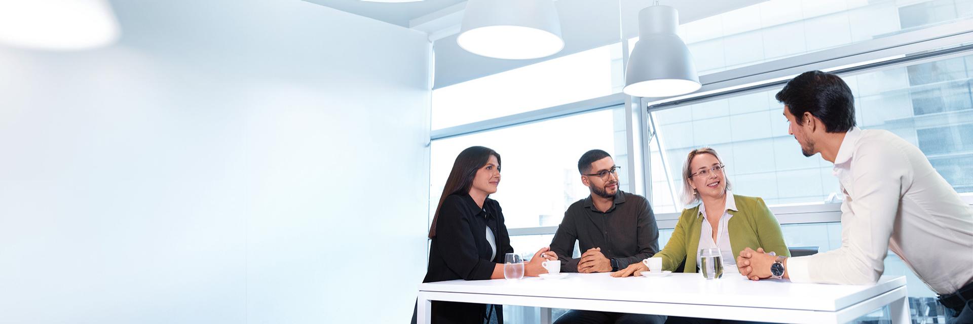 ZEISS Standort Portugal mit einem Übersichtsbild von vier lächelnden Mitarbeiter:innen in einem großen, hellen, verglasten Büro.