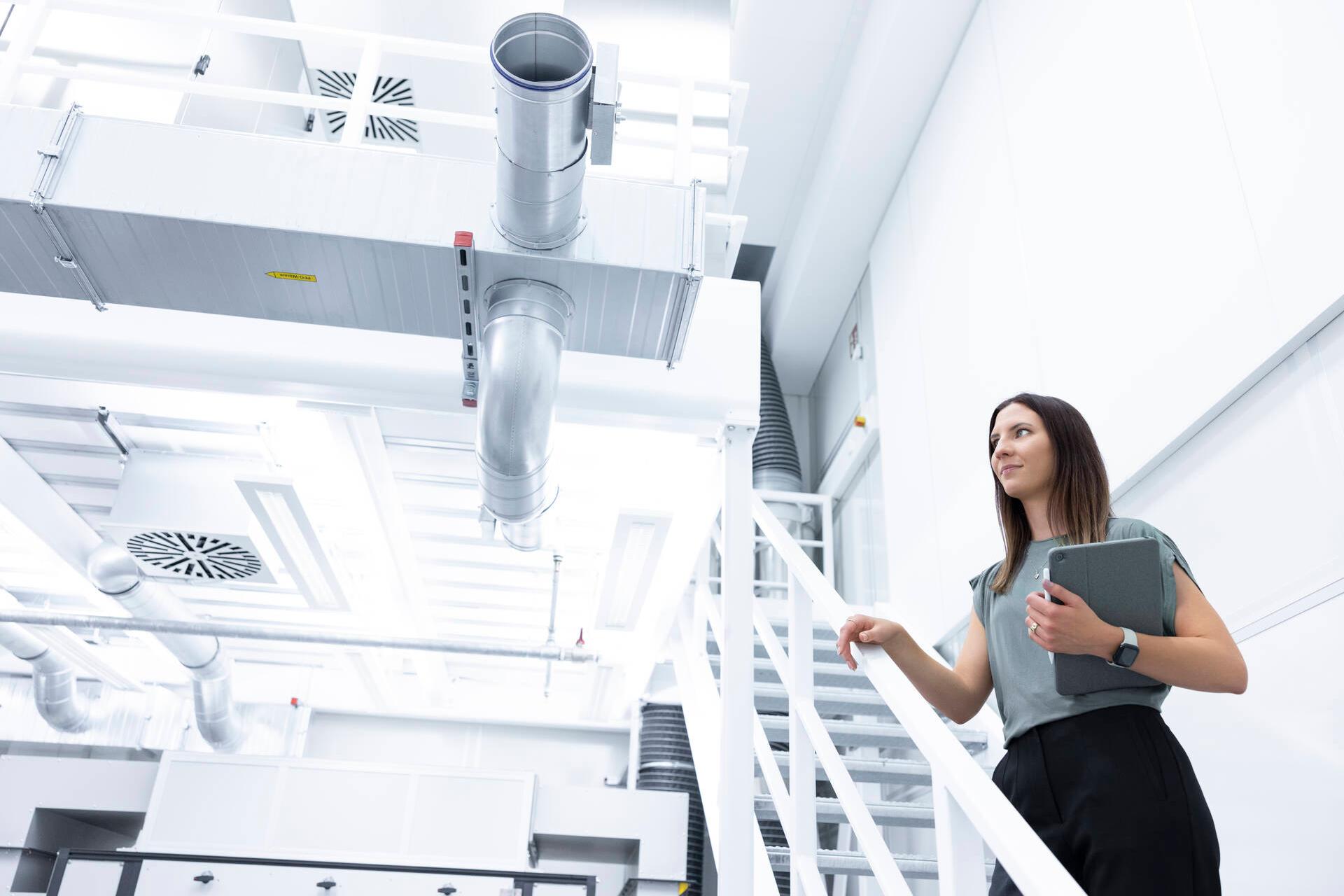 Marina steht auf einer Treppe in einer Produktionshalle
