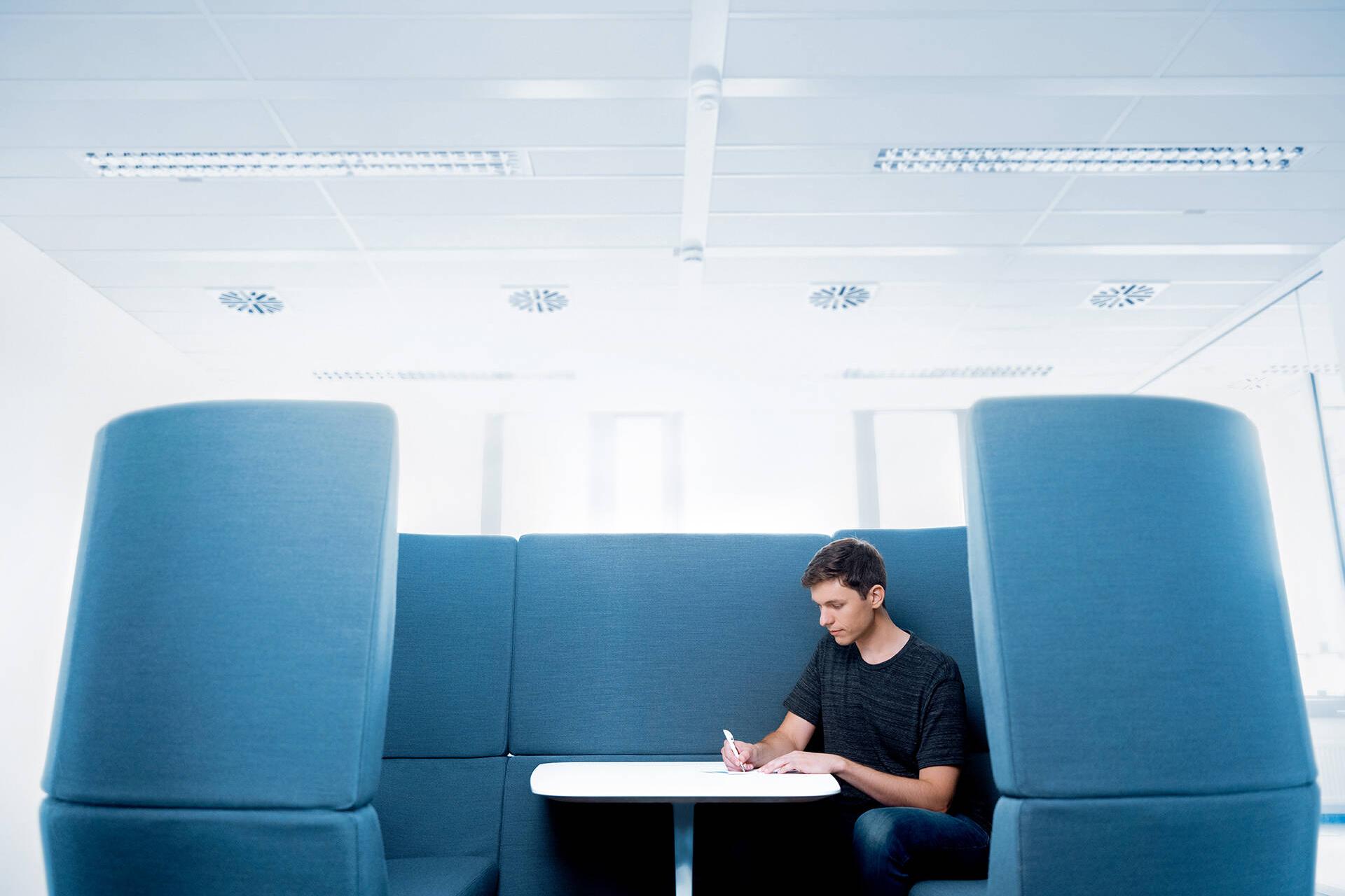 Eine männliche Person sitzt schreibend an einem Tisch
