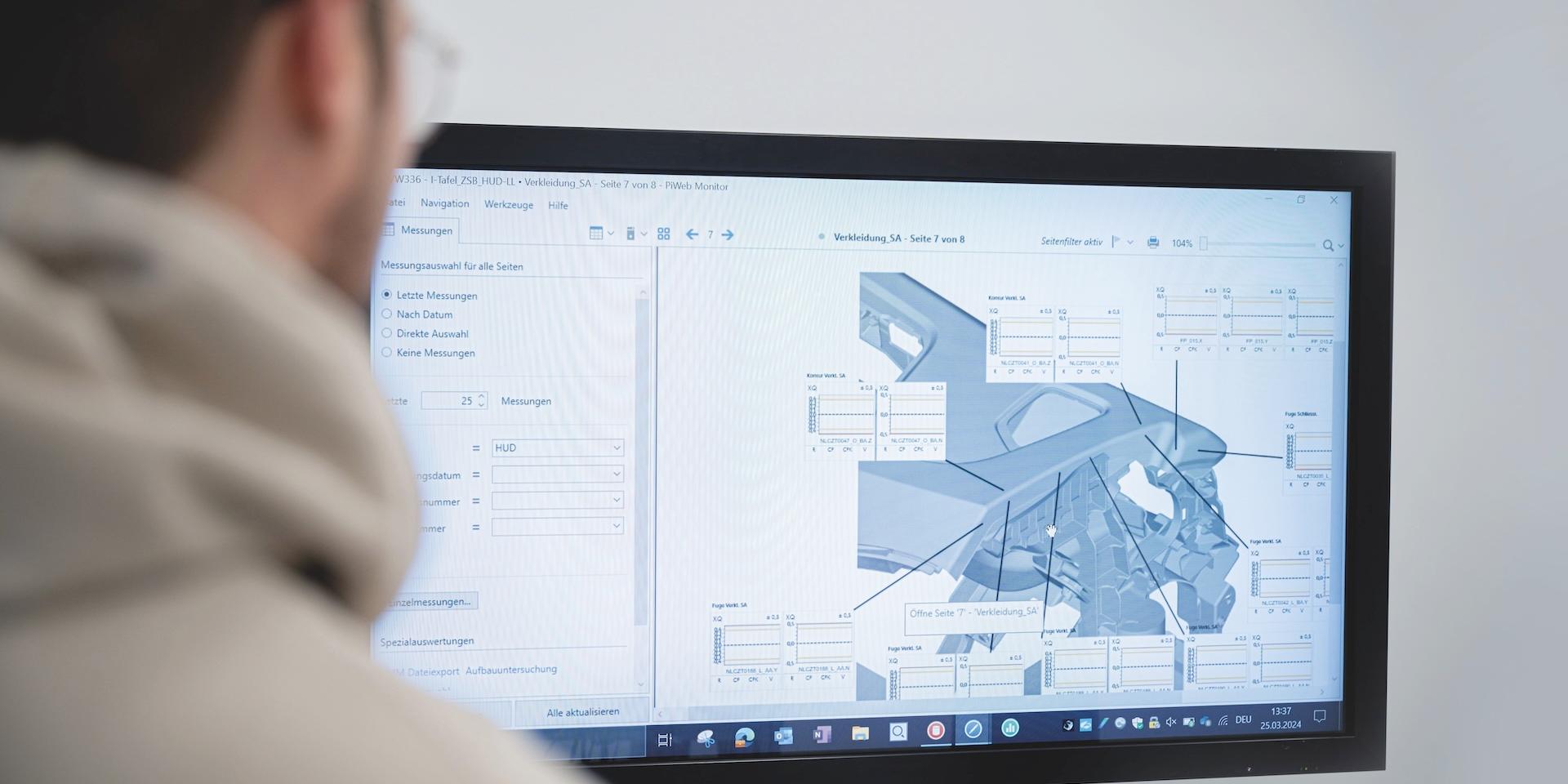 A person is looking at a large monitor displaying abstract visual data in a dark environment