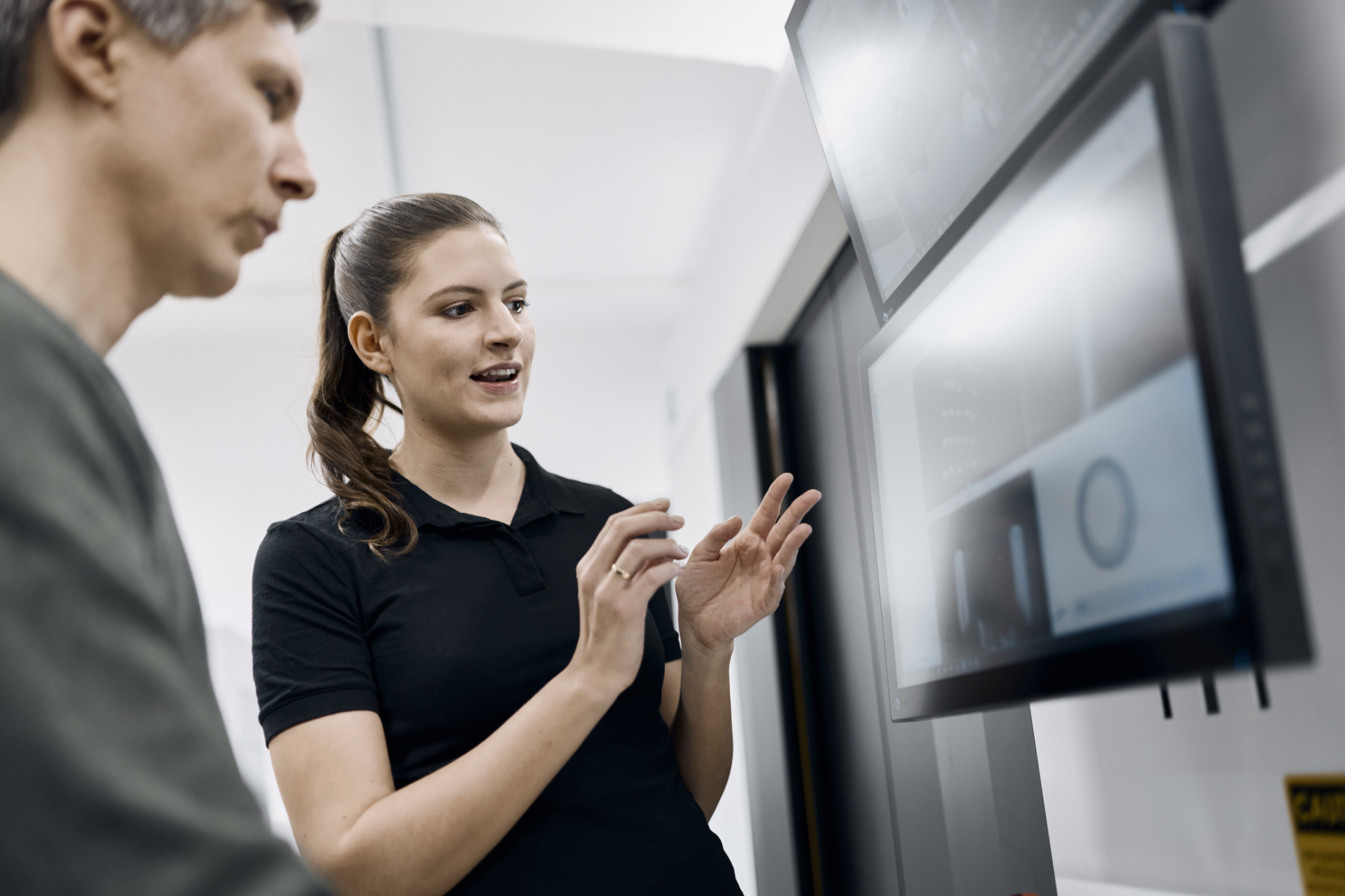 Two professionals are analyzing data on multiple monitors in a modern ZEISS laboratory or workspace.