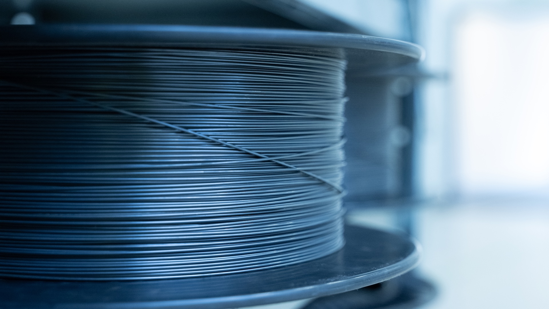 Close-up of a spool tightly wound with ultra-thin Nitinol wire in a clean, industrial setting at ZEISS.