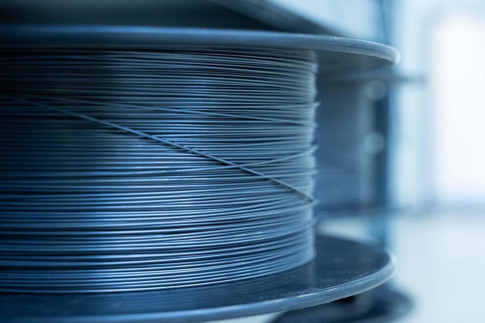 Close-up of a spool tightly wound with thin metallic wire in a clean, industrial setting at ZEISS.