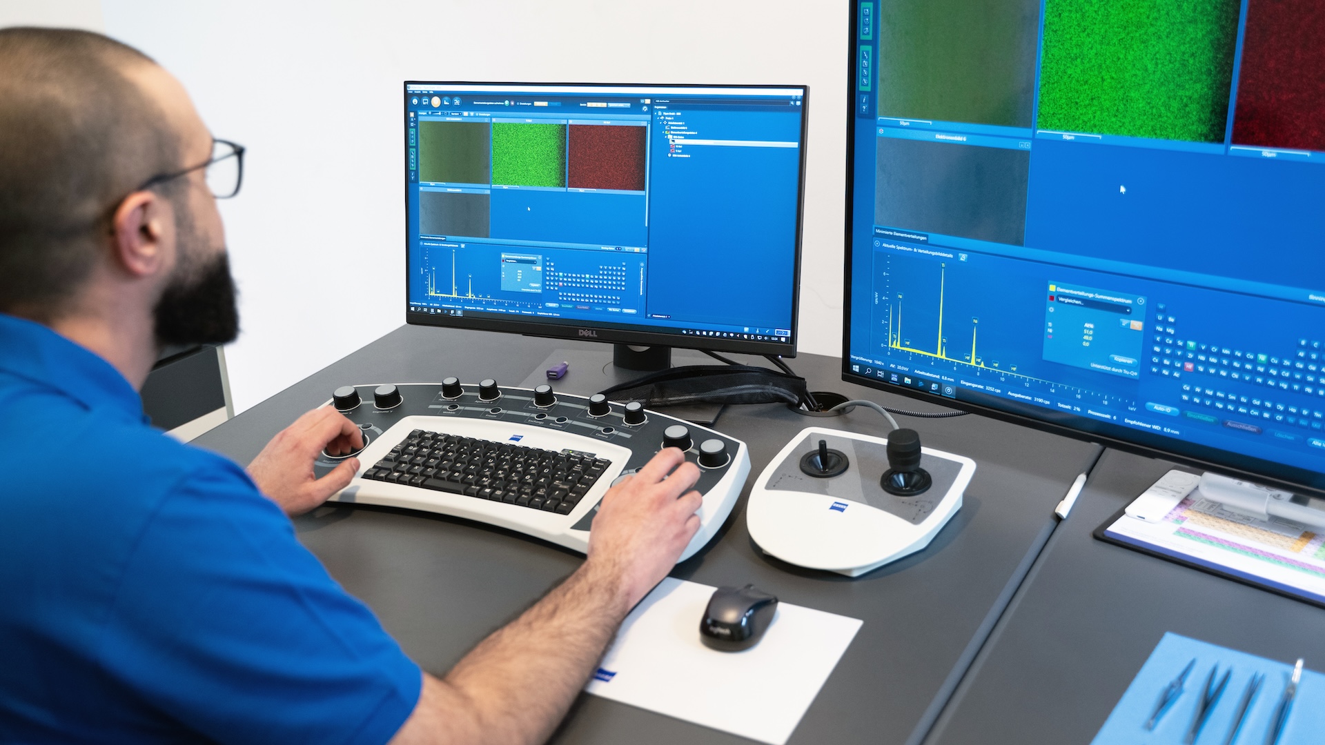 A technician operates ZEISS imaging software on dual monitors using a specialized control console in a laboratory setting.