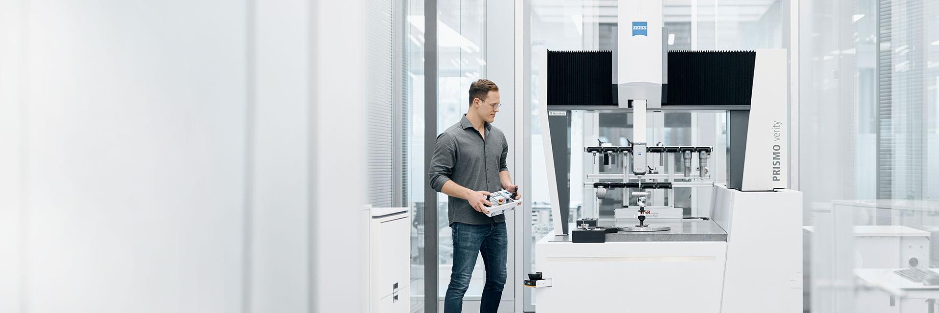 A metrology technician measuring a component with a ZEISS CMM calibrated according to DIN EN ISO 10360.