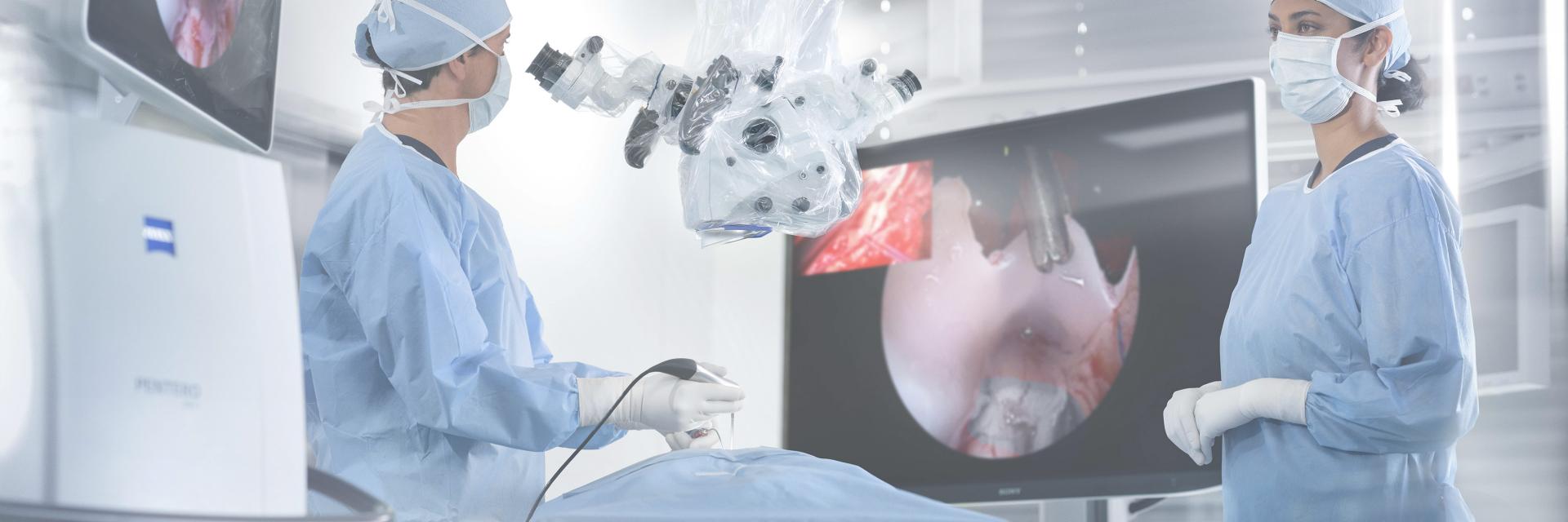 Two surgeons perform a procedure on a patient in a sterile operating room, focused on their task. 