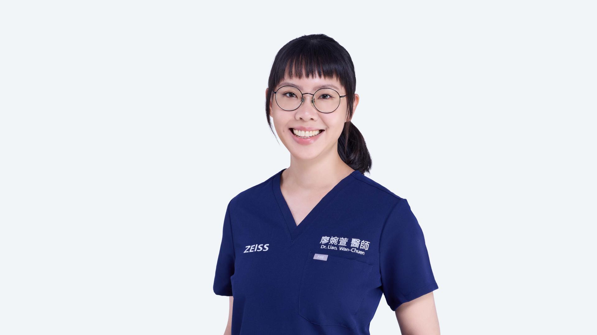 A woman wearing a blue shirt and glasses, smiling and looking towards the camera.