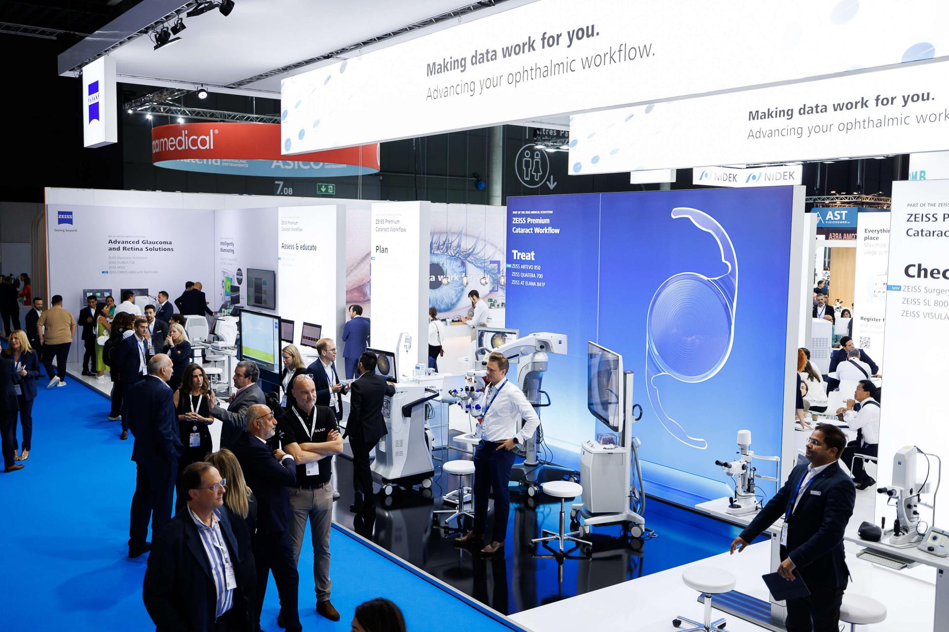 Visitors interact with advanced ophthalmic equipment and displays at the ZEISS exhibition booth during a professional medical trade show.